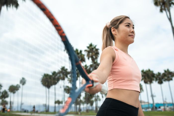 Woman in yoga outfit working out in a park with palm trees
